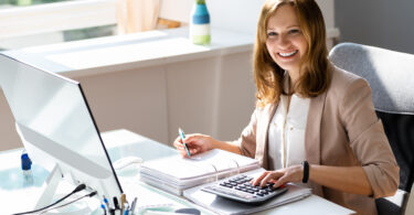 Professional accountant working on taxes at her desk with a calculator and computer