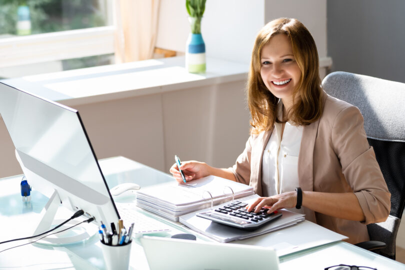 Professional accountant working on taxes at her desk with a calculator and computer