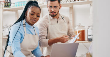 Two small business owners working on a computer in their shop.