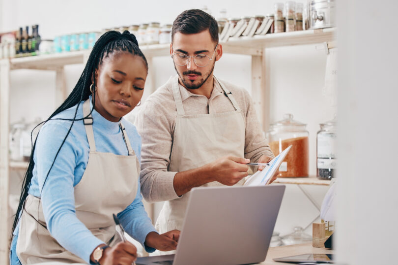 Two small business owners working on a computer in their shop.