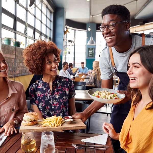 Waiter serving group of clients in restaurant