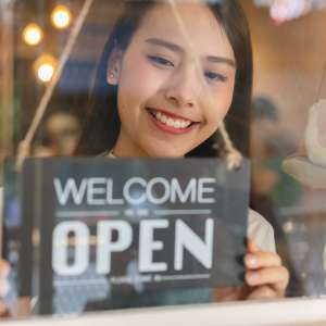 Female business owner with open sign at the door