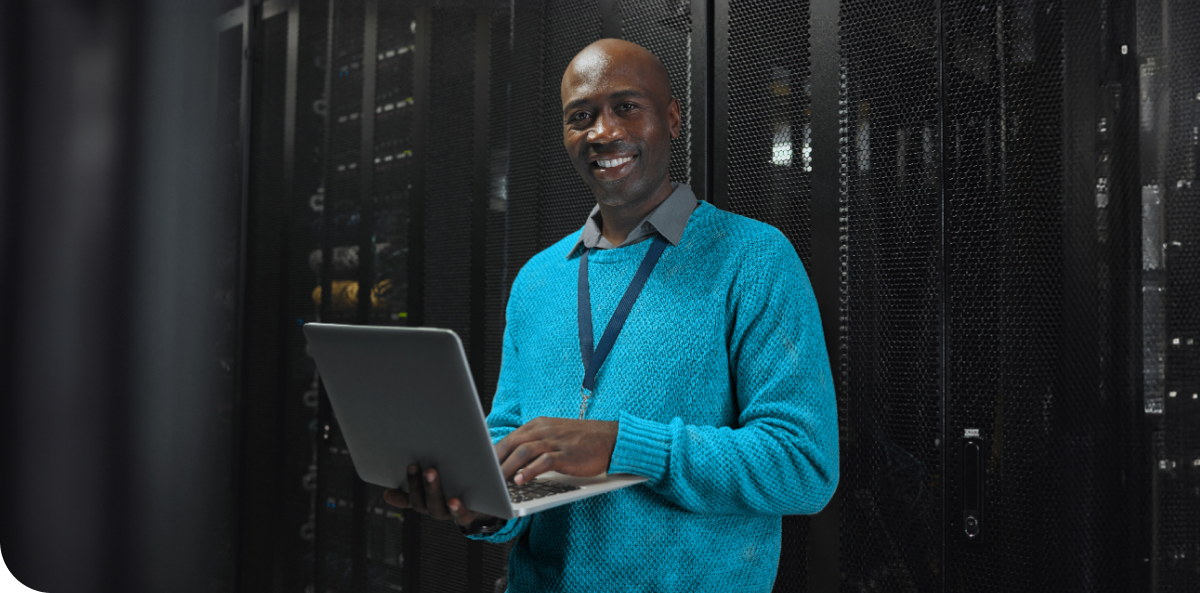 An IT professional holding a laptop, engaged in his work